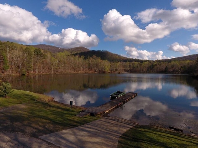 view of dock with a water and mountain view and a view of trees