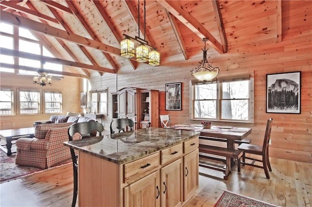 kitchen featuring wood walls, wood ceiling, light wood finished floors, and beamed ceiling