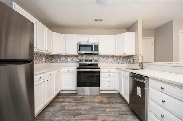 kitchen featuring visible vents, dark wood-style flooring, a sink, stainless steel appliances, and backsplash