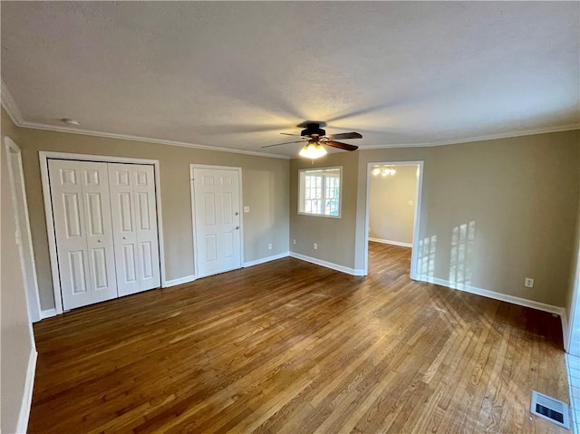 unfurnished bedroom featuring crown molding, wood finished floors, visible vents, and baseboards