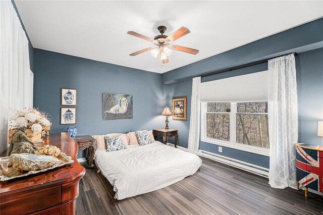 bedroom with dark wood-type flooring, ceiling fan, and a baseboard heating unit