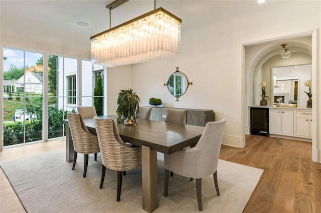 dining area featuring wine cooler, a chandelier, and light wood-type flooring