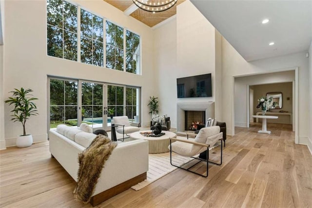 living room with a chandelier, a high ceiling, light hardwood / wood-style flooring, and french doors