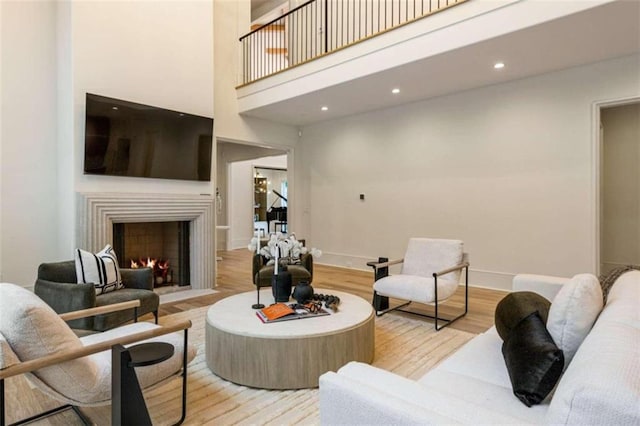 living room with a towering ceiling and light hardwood / wood-style flooring