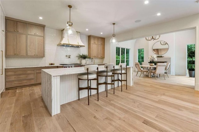 kitchen featuring pendant lighting, light hardwood / wood-style flooring, a large island, and custom exhaust hood