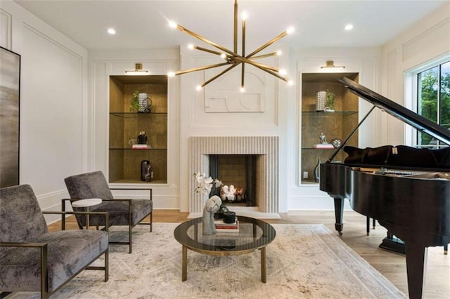 sitting room with built in features, a notable chandelier, and light wood-type flooring