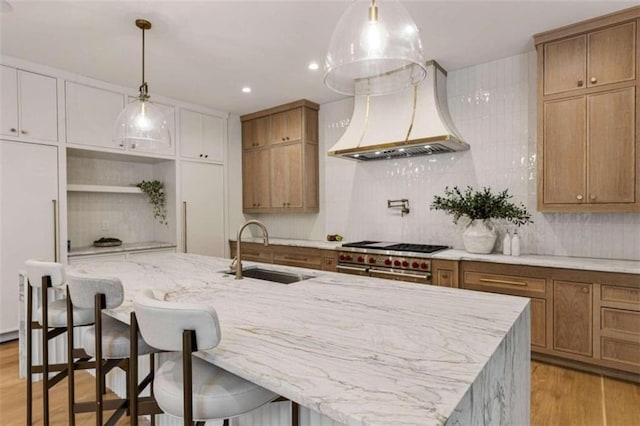 kitchen with sink, light hardwood / wood-style floors, decorative backsplash, a breakfast bar, and high end range