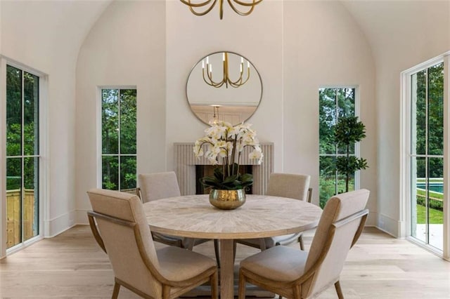 dining area with a notable chandelier, light wood-type flooring, and high vaulted ceiling