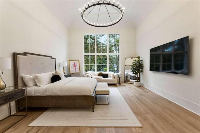 bedroom with light wood-type flooring, high vaulted ceiling, and a notable chandelier