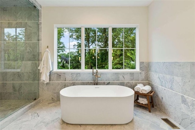 bathroom featuring a bath, tile walls, and a wealth of natural light