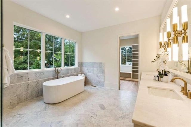 bathroom with a bath, a healthy amount of sunlight, and tile walls