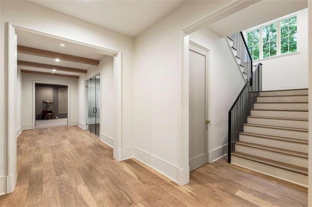 hall featuring beam ceiling and light hardwood / wood-style floors