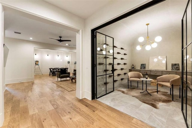 interior space featuring ceiling fan with notable chandelier and light wood-type flooring