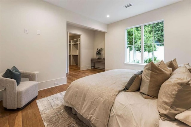 bedroom with hardwood / wood-style flooring, a walk in closet, and a closet