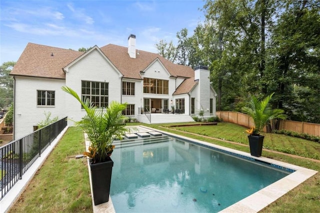 rear view of property featuring a yard and a fenced in pool