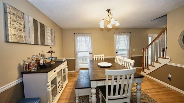 dining room featuring a notable chandelier, light wood-style flooring, baseboards, and stairs