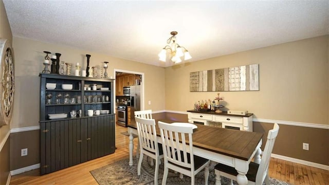 dining space featuring a chandelier, light wood-type flooring, and baseboards