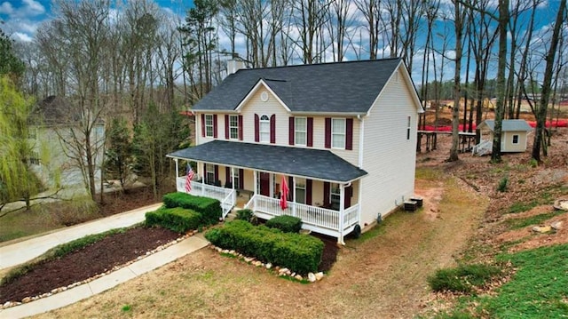 view of front of property with a chimney, a porch, and an outdoor structure