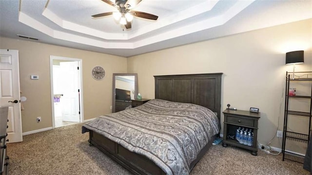 bedroom featuring a tray ceiling, visible vents, a ceiling fan, carpet flooring, and baseboards