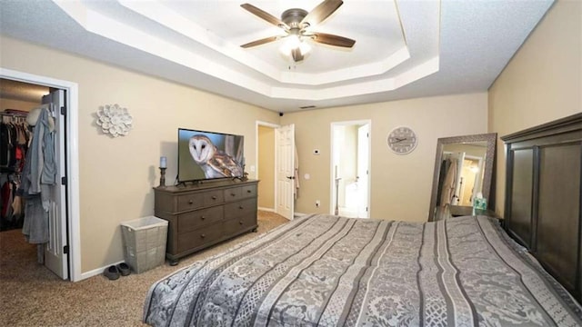 bedroom with carpet floors, baseboards, a spacious closet, a closet, and a tray ceiling