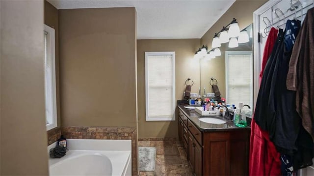 full bath with a textured ceiling, plenty of natural light, vanity, and a bath