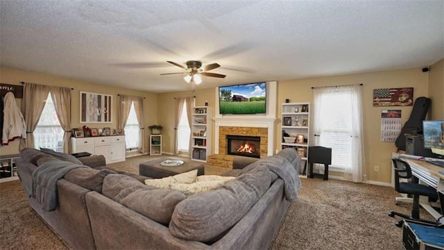 carpeted living room with a stone fireplace, ceiling fan, a textured ceiling, and baseboards