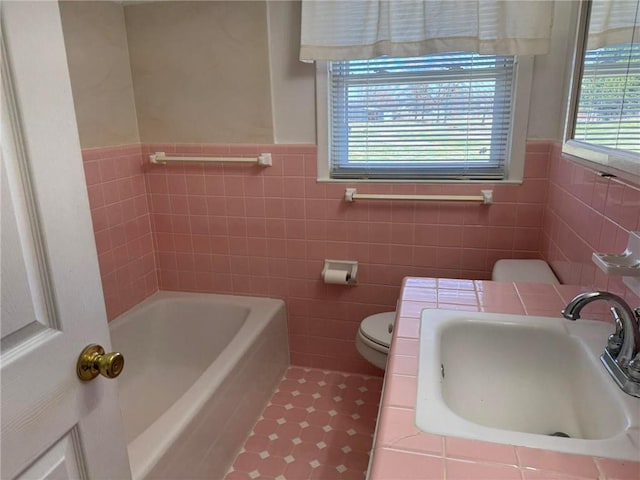 full bathroom with a tub to relax in, tile patterned flooring, a sink, and toilet