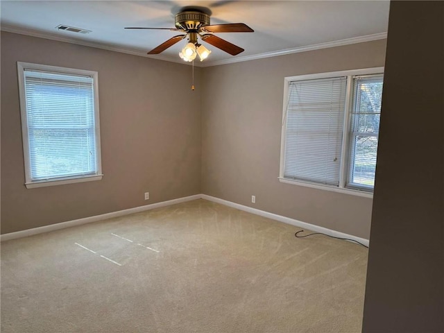 unfurnished room featuring carpet, crown molding, visible vents, a healthy amount of sunlight, and baseboards