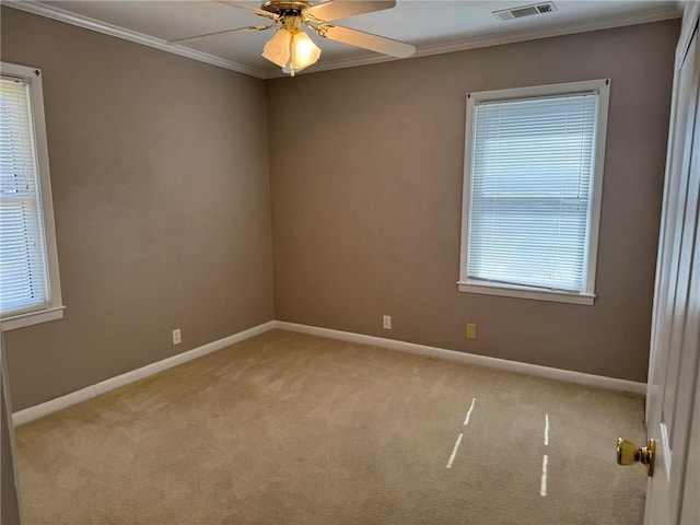 spare room with light colored carpet, visible vents, ornamental molding, ceiling fan, and baseboards