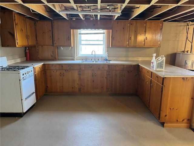 kitchen featuring brown cabinets, gas range gas stove, light countertops, a sink, and concrete flooring