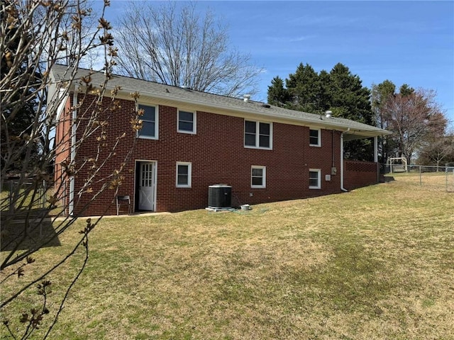 back of house featuring cooling unit, brick siding, a lawn, and fence