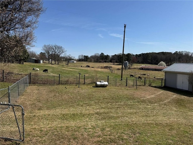 view of yard featuring a storage shed, a rural view, an outdoor structure, and fence