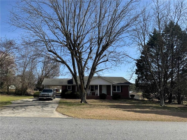 view of front of home featuring driveway, brick siding, and a front yard