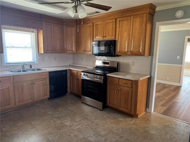 kitchen with brown cabinets, light countertops, visible vents, a sink, and black appliances