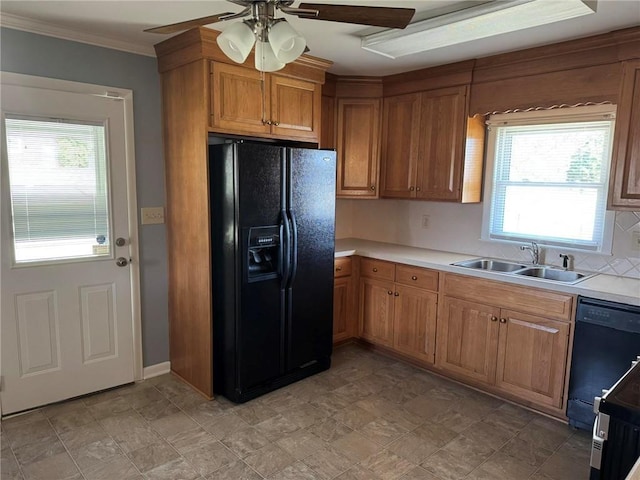 kitchen with crown molding, light countertops, brown cabinetry, a sink, and black appliances