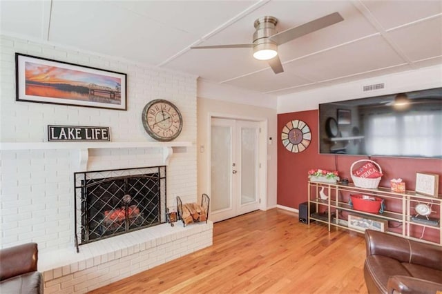 living room with ceiling fan, a fireplace, and wood-type flooring