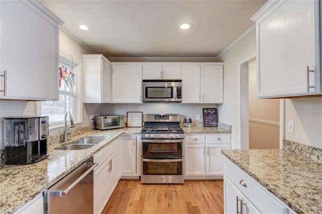 kitchen with sink, crown molding, light stone counters, appliances with stainless steel finishes, and white cabinets