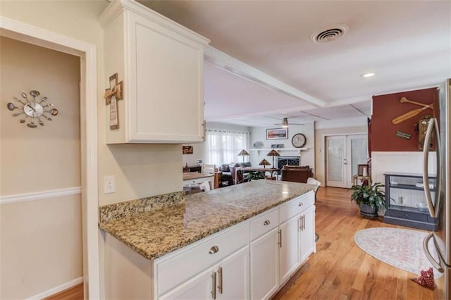 kitchen with light hardwood / wood-style flooring, light stone countertops, a large fireplace, and white cabinets