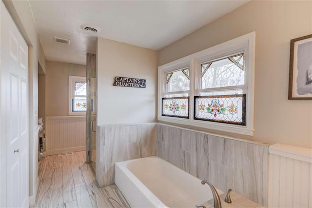 bathroom featuring hardwood / wood-style floors, radiator heating unit, and a washtub