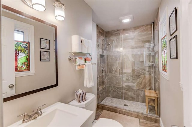 bathroom featuring toilet, a shower with shower door, and sink