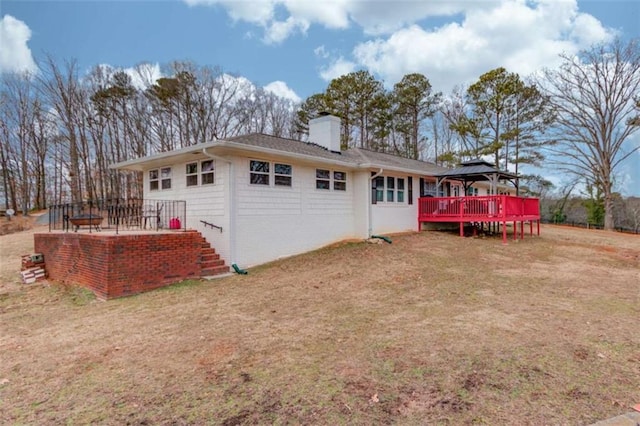 rear view of property featuring a gazebo, a yard, and a wooden deck