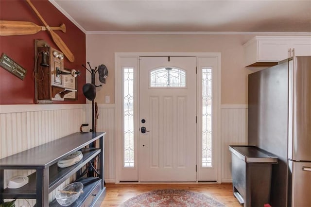 foyer entrance featuring crown molding and light hardwood / wood-style floors