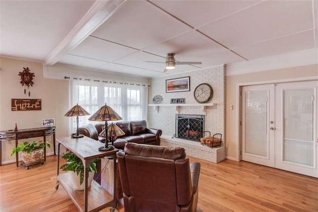 living room featuring ceiling fan, a brick fireplace, and light hardwood / wood-style flooring