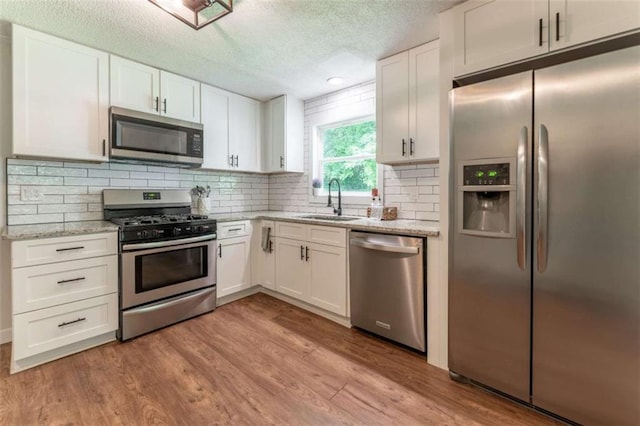361 Princeton Way, Lawrenceville, GA 30044 - kitchen with stainless steel appliances, white cabinets, light wood-type flooring, a textured ceiling, and light stone countertops