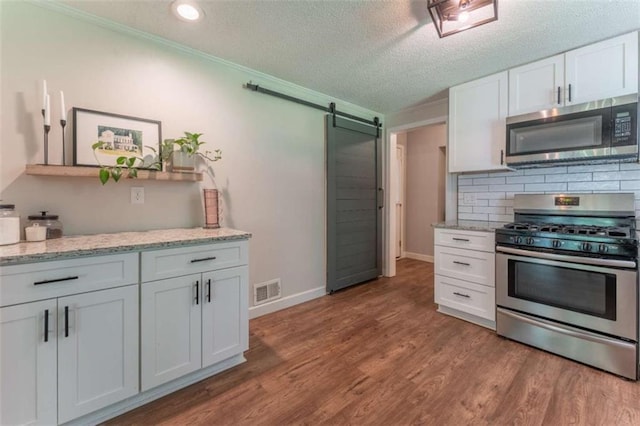 361 Princeton Way, Lawrenceville, GA 30044 - kitchen featuring stainless steel appliances, a barn door, white cabinetry, light wood finished floors, and ornamental molding