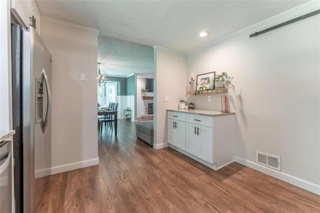 361 Princeton Way, Lawrenceville, GA 30044 - bar area featuring stainless steel fridge with ice dispenser, a textured ceiling, crown molding, wood finished floors, and a brick fireplace