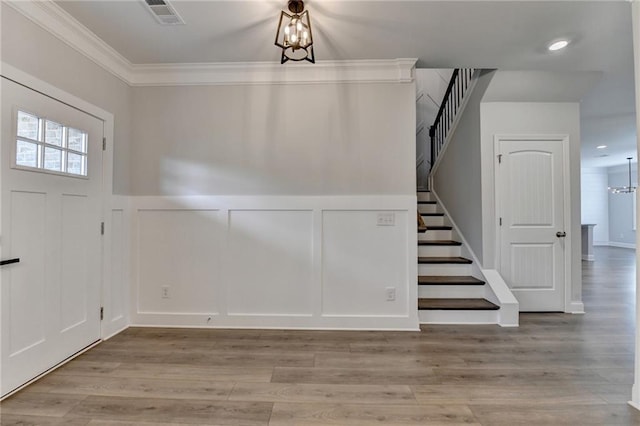 2090 Harvester Ln, Buford, GA 30518 - entryway featuring a decorative wall, stairs, wood finished floors, a wainscoted wall, and crown molding