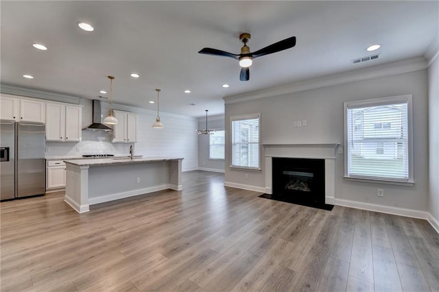 2090 Harvester Ln, Buford, GA 30518 - kitchen featuring stainless steel fridge, wall chimney exhaust hood, plenty of natural light, ornamental molding, and white cabinetry