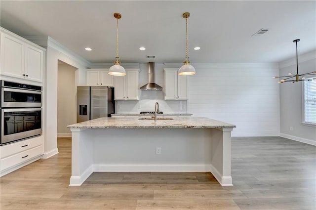 2090 Harvester Ln, Buford, GA 30518 - kitchen featuring appliances with stainless steel finishes, wall chimney exhaust hood, white cabinetry, a kitchen island with sink, and a chandelier