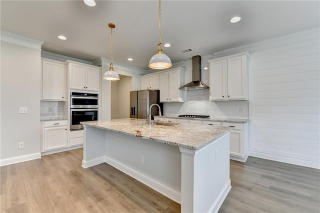 2090 Harvester Ln, Buford, GA 30518 - kitchen featuring wall chimney range hood, stainless steel appliances, backsplash, a kitchen island with sink, and light wood finished floors